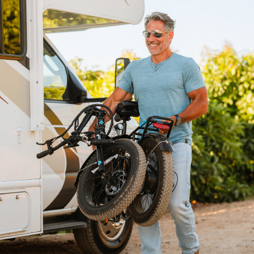 man carrying Lectric bikes folded in from of his RV