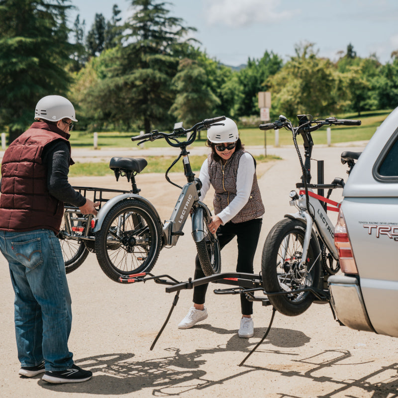 Couple taking off Lectric XP Trike off of a bike rack attatched to their SUV