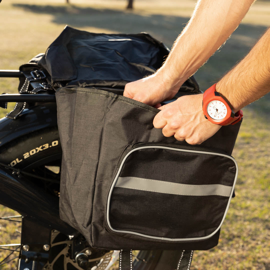 Hands are visible reaching into a pannier bag on the back of a bike